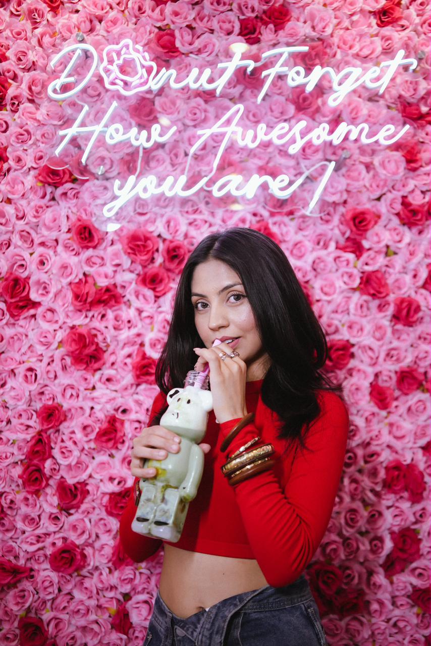 A customer enjoying a Bober Tea drink beside the pink flower wall