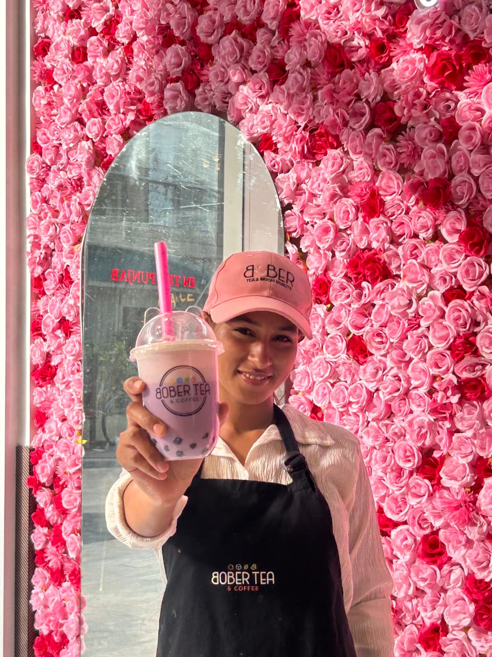 Bober Tea team member holding a freshly prepared pink drink